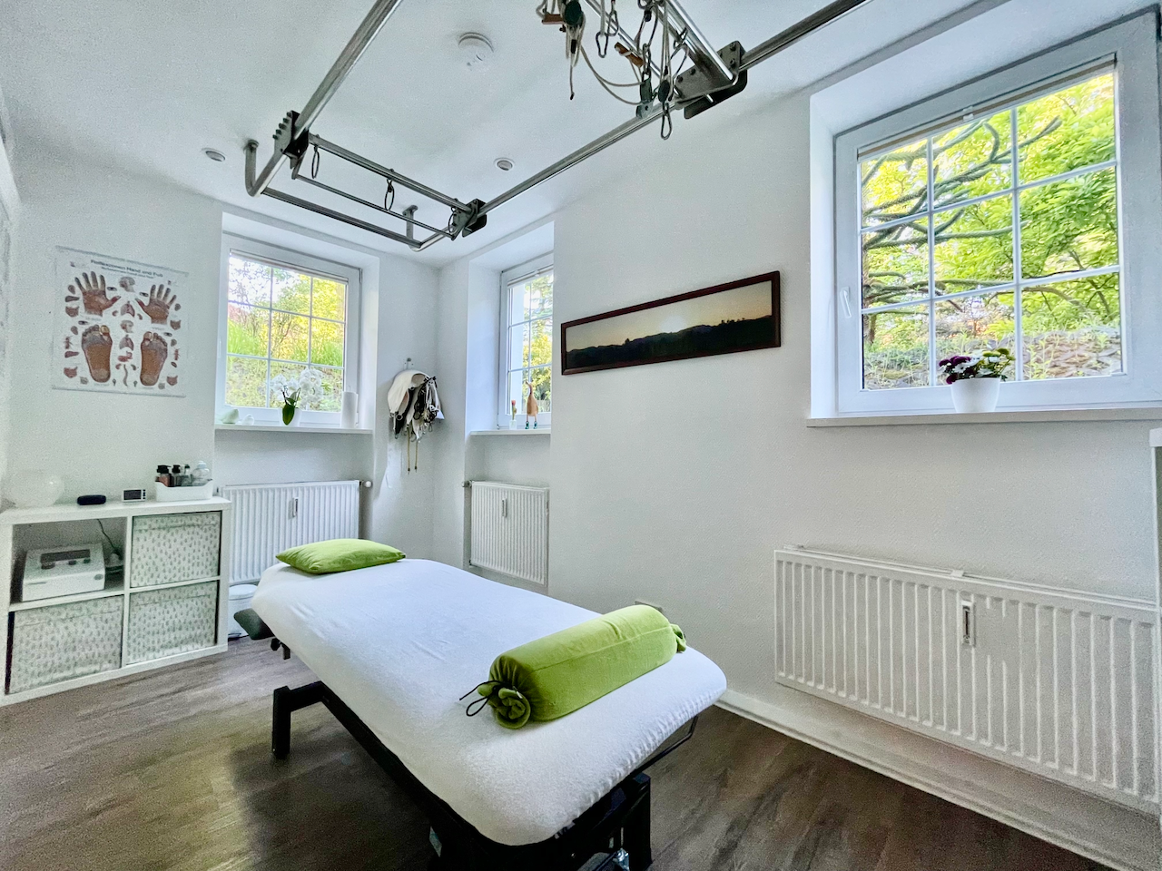 Heller Behandlungsraum mit Therapieliege und Schlingensystem